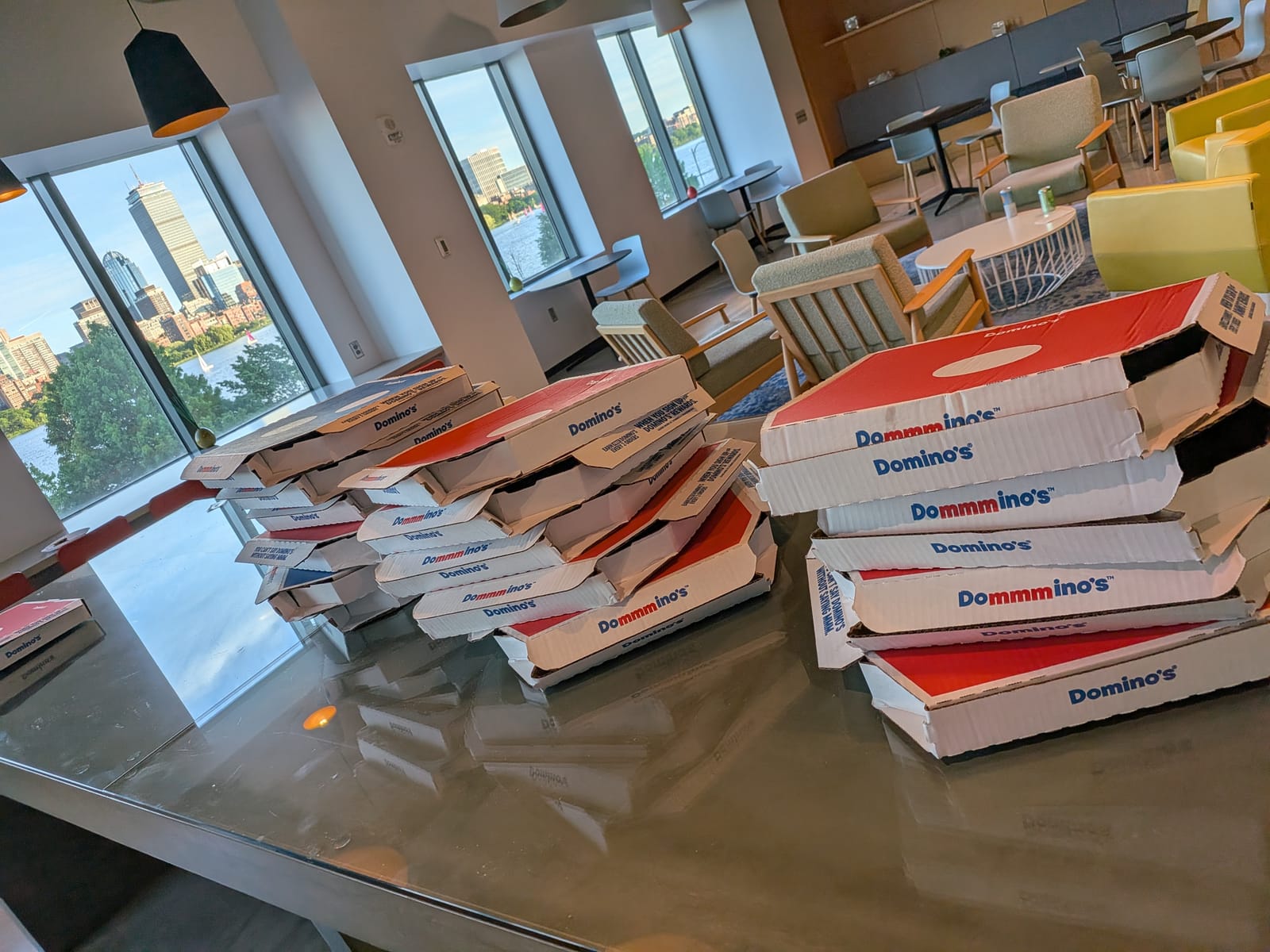 Stacked pizza boxes with the Boston skyline through the window before doors